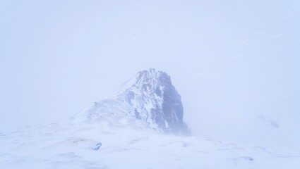 Snowy mountain peak shrouded in mist and clouds offering a sense of coldness and desolation in the winter season