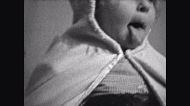 Film archive, funny little child portrait sticking out tongue, close up. Cute playful baby toddler have fun in vintage indoors. Childhood humor. Adorable girl at family home. Old archival retro 1960s