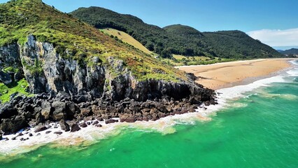 An incredibly beautiful aerial view showcasing lush green cliffs, a serene beach, and stunning...