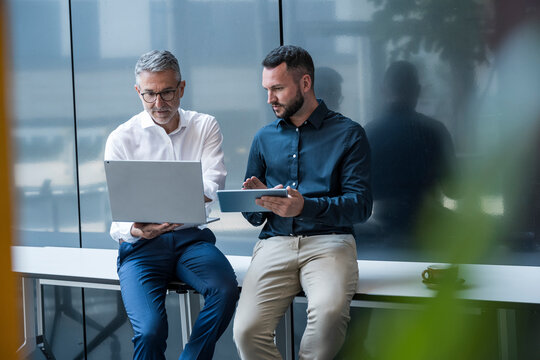 Business colleagues discussing work using laptop and tablet in office