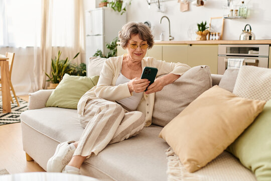 Senior woman enjoying a relaxing afternoon at home while browsing on her smartphone