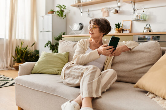 Senior woman relaxing at home in cozy attire while using her smartphone