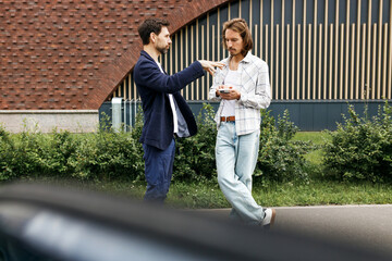 Side view of two men talking outside like having business appointment, brunette man gesticulating...