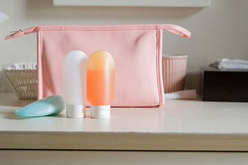 travel sized plastic containers for toiletry and pink cosmetic bag on table in the hotel room