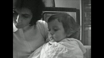 Old archive, caring mother feeding baby with spoon in retro indoor, close up. Cute small child eat home food. Tender motherhood care. Vintage film childhood. Archival retro 1960s. Breakfast nutrition - Powered by Adobe