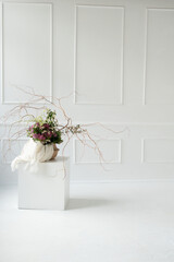 minimalistic floral arrangement with purple and green blooms on cubic pedestal in bright white room with geometric wall patterns, creative, composition, aesthetic, neutral, symmetrical, harmonious