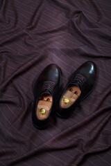 Male classic formal dark brown leather shoes on fabric suit background. Copy space for logo design,...