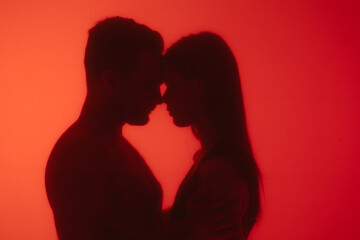 Silhouetted Couple Kissing Behind a Red Glass Surface