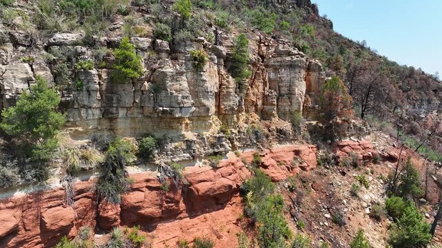 Aerial view of layered rock formations displaying a spectrum of earthy tones, from deep reds to pale yellows, Pine, Arizona, United States.