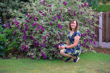 Crouching beside a variegated buddleia, in July, 2025.