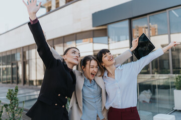 Group of three young women expressing joy and camaraderie outdoors. They display teamwork and...