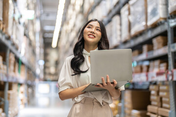 Female engineer is handling shipping and checking stock inventory in the warehouse with a laptop,...