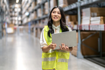 Female engineer is handling shipping and checking stock inventory in the warehouse with a laptop,...