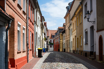 Fototapeta premium Colorful old residential street with cobblestone pavement and historic facades in Wismar, Germany