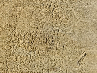 sand Rough yellow stucco wall texture with a natural grainy surface and visible imperfections. Close-up detail of plaster or concrete surface with uneven finish. Perfect as a background, overlay textu