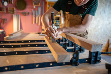 Final inspection of wooden beams for smoothness and flatness with chisel removing imperfections...