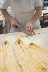 Traditional italian cook cutting pasta. Delicious homemade cuisine. Tagliatelle