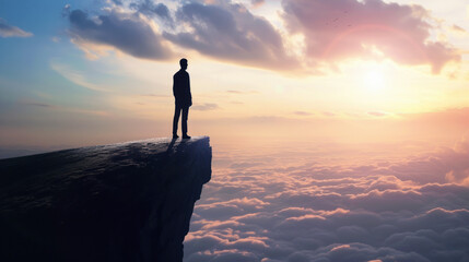 Silhouette of a person standing on a cliff overlooking a sea of clouds at sunset, symbolizing achievement.