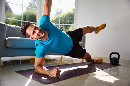 Man at home doing side plank star exercise - Powered by Adobe