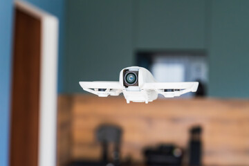 A drone with a security camera hovers in the air inside a house. Concept of smart home, security,...
