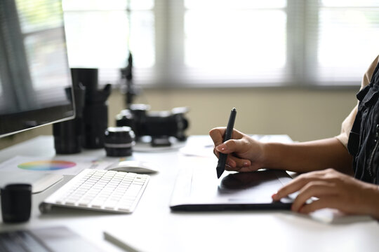 Close up of designer working on a digital drawing tablet in a home office - Powered by Adobe