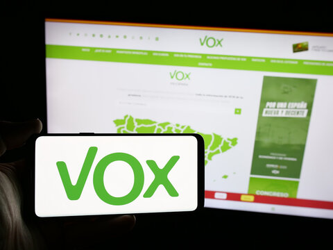 Stuttgart, Germany - 07-18-2025: Person holding smartphone with logo of Spanish political party Vox on screen in front of website. Focus on phone display.