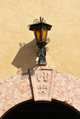 Traditional Outdoor Iron Lamp on Wall above Keystone with Sign 'PB 1897' 