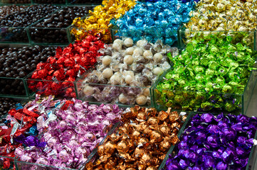 Bulk bins filled with an assortment of colorful, foil wrapped candies.