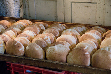 Freshly baked round pita or pocket bread neatly stacked in a wooden tray ready for delivery in the Machane Yehuda market in Jerusalem, Israel.