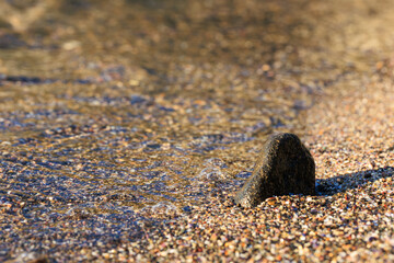 sea wave on the shore and a little black rock in the sand for grafik and design purposes