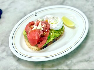 Avocado toast topped with juicy tomato slices and a perfectly poached egg — simple, nourishing, and always satisfying. Jakarta, Indonesia - June 18, 2025