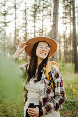 Young caucasian woman hiking or trekking through scenic forest with hiking sticks during golden hour