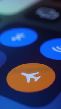 Get ready for takeoff. Close up smartphone screen flicks airplane icon with your finger to activate airplane mode on mobile phone. Disable wireless network and sound.