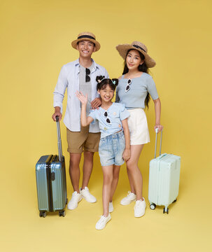 happy Asian family of three including a father mother and daughter dressed in summer attire ready for fun vacation with their luggage.