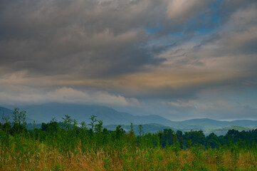 A stormy sky sunrise in Cades Cove, with the storm clouds just beginning to break up and still looking angry and heavy with rain and the Great Smoky Mountains