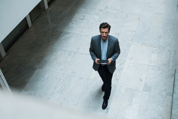 Obraz premium Overhead shot of businessman walking confidently in office hallway