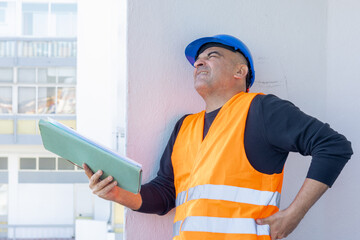 Injured construction worker or engineer suffering backpain. A warehouse worker in pain holding his back and making painful grimace