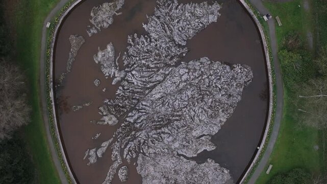 Aerial view of the Scotland Relief Map, a captivating display of earth tones contrasted by the surrounding green landscape, Peebles, Scotland, United Kingdom.