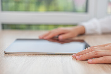 A person in a white shirt interacts with a tablet on a white table.