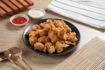 Crispy Popcorn Chicken with sauce and mayonnaise on a black plate. Perfect for recipes, articles or any cooking content.
