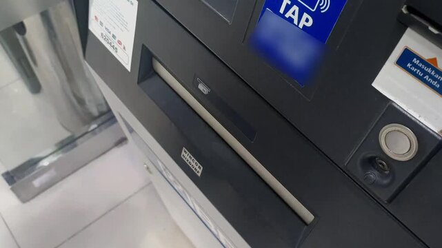 Female hand withdrawing Indonesian cash from ATM (Automatic Teller Machine) - Indonesian banknotes