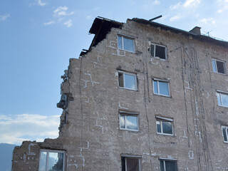 Partially collapsed building against blue sky and clouds