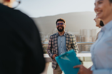 A group of joyful business people celebrating success on a high tower balcony at sunset, enjoying...