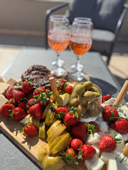 A summer snack platter with fruits, nuts, and savory snacks on a table with glasses, perfect for outdoor terrace gatherings. Refreshing, casual summer dining experience.