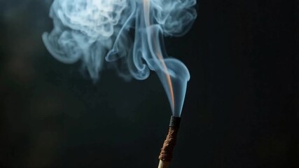 Aromatic smoke rising from an incense stick against a dark background