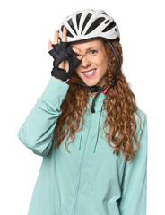 Young redhead cycling in studio excited keeping ok gesture on eye.