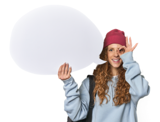 Redhead holding a comic speech bubble excited keeping ok gesture on eye.