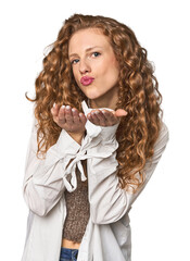 Simple redhead studio portrait folding lips and holding palms to send air kiss.