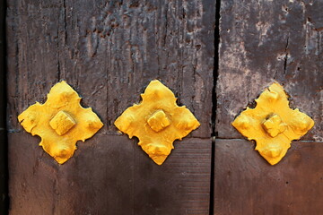 Ferrures dorées sur porte ancienne en bois.