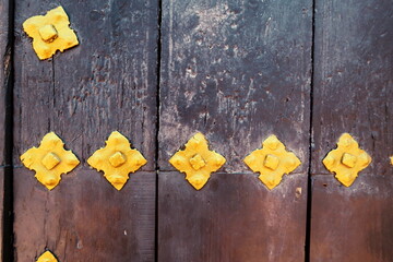 Ferrures dorées sur porte ancienne en bois.